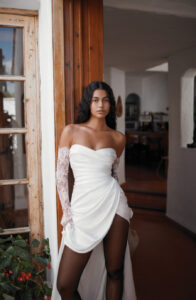 Dana Harel Danielle wedding dress from a bridal shop in Chicago. The model is showing her black tights and looking directly at the camera.