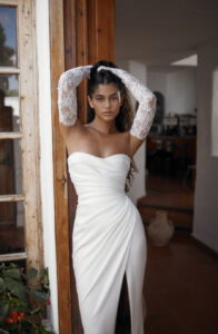 Dana Harel Danielle wedding dress from a bridal shop in Chicago. The model is holding her hair back and looking directly at the camera