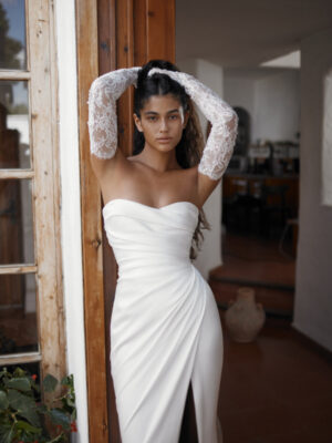 Dana Harel Danielle wedding dress from a bridal shop in Chicago. The model is holding her hair back and looking directly at the camera