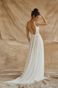 A model is standing on drop cloths wearing a Nara by Dana Harel wedding dress from a bridal shop in Chicago, IL.