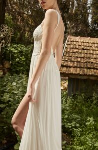 A close-up of a model's side wearing a Nara by Dana Harel wedding dress from a bridal shop in Chicago, IL. The dress has a slit in the leg.