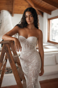 Dana Harel Venice Wedding Dress from a Bridal Shop in Chicago, IL. The model is posing with her arm on a ladder.