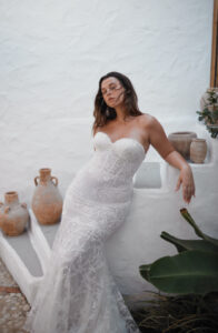 Dana Harel Venice Wedding Dress from a Bridal Shop in Chicago, IL. The model is posing in front of a white stucco stairwell.