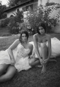 Dana Harel Kim wedding dress from a bridal shop in Chicago, IL. Two models are sitting on the ground in front of a Mediterranean style home.