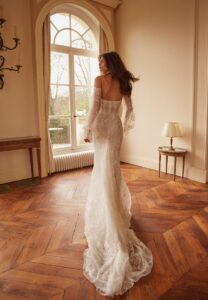 A model shows off her fit and flare wedding dress with whimsical off-the-shoulder long sleeves. The dress is "Sally" by Netta BenShabu and is available through Mira Couture in Chicago, IL