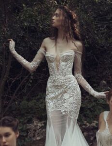 Kim Kassas Daphne Wedding Dress with plunging neckline, applique, corset, lace, sheer skirt, and mermaid train available at a bridal shop in Chicago, IL