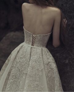 The back of a model wearing a Kim Kassas Helice Wedding Dress with floral blush lace detailing. Available at a bridal shop in Chicago, IL.