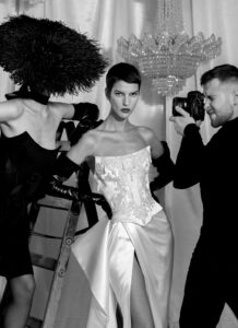 A model wearing a Noemie wedding dress by Kim Kassas. The dress is satin, features a corset, and thigh-high slit. Available at a bridal shop in Chicago, IL