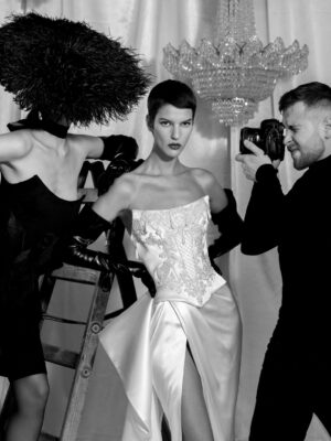 A model wearing a Noemie wedding dress by Kim Kassas. The dress is satin, features a corset, and thigh-high slit. Available at a bridal shop in Chicago, IL