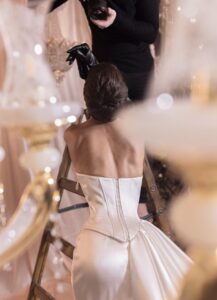 The back of a model wearing Noemie by Kim Kassas wedding dress. The satin dress features a corset. Available at a bridal shop in Chicago, IL