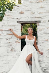 Martina Liana 1684 Wedding Dress romantic fit and flare style featuring a slit, a delicate square neckline, and a tight bodice at a bridal shop in Chicago, IL.