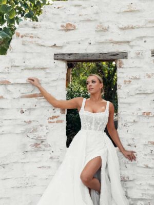 Martina Liana 1684 Wedding Dress romantic fit and flare style featuring a slit, a delicate square neckline, and a tight bodice at a bridal shop in Chicago, IL.