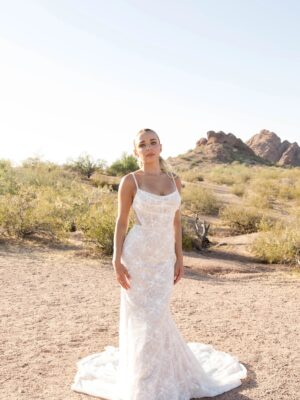 A model wears Martina Liana 1697 Wedding Dress available at a bridal shop in Chicago, IL. The bridal gown has beading, a corset, is fit and flare style and has a sheer overlay.