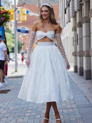 A model in Chicago, IL faces the camera in the Araceli by Calla Blanche wedding dress. It is a modern and flirty two-piece set that features a strapless sweetheart bodice and a vintage tea-length skirt.