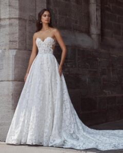 Full view of a model wearing a romantic sweetheart ballgown wedding dress with delicate floral lace and a soft train from bridal shop Mira Couture in Chicago, IL.