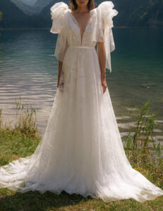 A model shows the front of her BRT008 by Daalarna wedding dress which is an ethereal soft tulle A-line bridal gown with a plunging v-neckline and unique floral embroidery trickling down the skirt. It is available at a bridal shop in Chicago, IL.