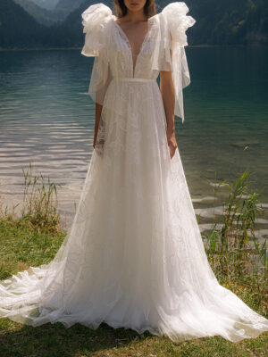 A model shows the front of her BRT008 by Daalarna wedding dress which is an ethereal soft tulle A-line bridal gown with a plunging v-neckline and unique floral embroidery trickling down the skirt. It is available at a bridal shop in Chicago, IL.