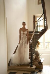 A bride wearing the Lily by Dana Harel wedding dress. It is a feminine soft A-line made out of a beautiful tulle skirt. It features delicate Calla Lily flowers cascading from the bodice down the train, creating an illusion-like painting on the body.