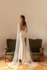 A model with her back to the camera wearing the bold and glamorous beaded fitted gown Perla by Eva Lendel that features a plunge neckline and an elegant open back.