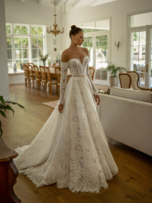 A bride shows the Pier by Neta Dover wedding dress. It's a romantic Chantilly lace ballgown featuring a sweetheart neckline and charming lace long sleeves. It's available at a bridal shop in Chicago, IL.