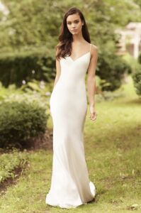 A model steps forward, showcasing the back of the 5080 by Paloma Blanca wedding dress. The bridal gown is made of charmeuse satin and features a bias cut, a V-neckline, a low back, and delicate strap ties. This dress is available at a bridal shop in Chicago, IL.