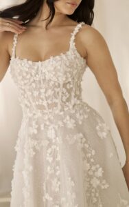 A close-up image of the 1718 by Martina Liana wedding dress with 3D floral details and a square neckline. This bridal gown is available at a bridal shop in Chicago, IL.