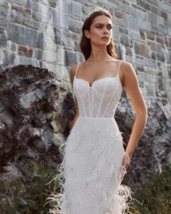 A close-up view of a bride showing her fitted, sparkly wedding dress, 124125 Bryony by Calla Blanche. The bridal gown features feathers and spaghetti straps and is available at a bridal shop in Chicago, IL.