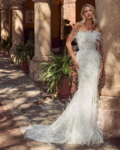 Fitted wedding gown with feathers and a strapless neckline. 