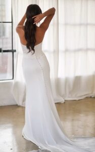 A rear view of a bride wearing the 1906 by Martina Liana wedding dress. The column gown features a strapless sweetheart neckline and draped detailing to complement the structured corset bodice. It is available at a bridal shop in Chicago, IL.