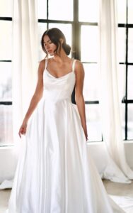 A bride lowers her eyes while wearing the 1766 wedding dress by Martina Liana. The clean ballgown utilizes high-shine silk fabric and features an oversized detachable bow. This bridal gown is completed with fabric-covered buttons from the waist to the end of the train. Available at a bridal shop in Chicago, IL.