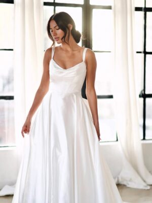 A bride lowers her eyes while wearing the 1766 wedding dress by Martina Liana. The clean ballgown utilizes high-shine silk fabric and features an oversized detachable bow. This bridal gown is completed with fabric-covered buttons from the waist to the end of the train. Available at a bridal shop in Chicago, IL.