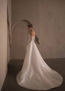 A side view of a bride's wedding dress, Tamara by Neta Dover. The two-piece bridal gown has a corset lace bodice and a full skirt to complete the A-line silhouette. It's available in Chicago, IL.