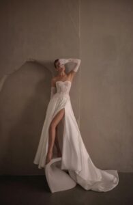 A bride covers her face while showing her wedding dress, Tamara by Neta Dover. The bridal gown is strapless with a sweetheart neckline and is paired with lace gloves. This two-piece A-line gown is available in Chicago, IL.