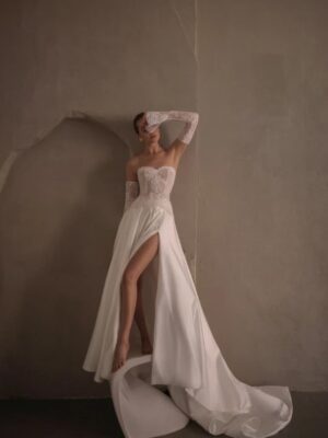 A bride covers her face while showing her wedding dress, Tamara by Neta Dover. The bridal gown is strapless with a sweetheart neckline and is paired with lace gloves. This two-piece A-line gown is available in Chicago, IL.