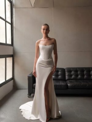 A bride faces the camera showing the slit of her Tommy by Neta Dover wedding dress. The bridal gown features a fitted corset bodice and is available in Chicago, IL.