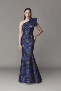 One shoulder evening gown with front draping and bow and a fit and flare skirt silhouette.