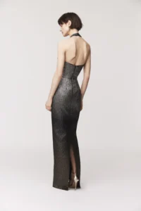 Halter gown Collar band with back covered button and open back Column skirt silhouette with back slit Exposed black zipper Satin lined metallic ombre