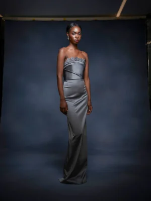 This strapless column gown is made from luxurious stretch satin, creating a sleek and flattering silhouette. It features a stunning beaded neckline that adds a touch of elegance, making it perfect for formal occasions.