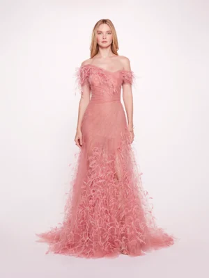 This stunning gown features a vibrant flamingo pink hue, elegantly crafted from soft tulle. The off-the-shoulder design adds a touch of romance, while delicate feather accents enhance the overall whimsy. The flattering A-line silhouette flows gracefully, making it perfect for any special occasion. Experience the perfect blend of elegance and playful charm in this exquisite piece.