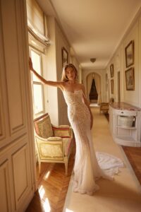 he Calypso gown features a soft peaked sweetheart neckline and a corset bodice, beautifully adorned with dangling beaded freshwater pearls. This fit-and-flare wedding dress showcases a flowing train and an elegant open back.