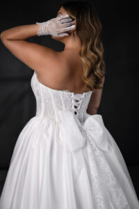 Chantilly lace basque waist corset bodice with a strapless design, featuring a clean ballgown silhouette. The gown is accented with a scalloped edge sweetheart neckline and a tulle lace-up back for a romantic finish.