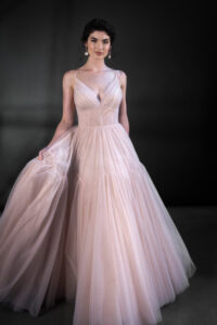 This captivating V-neck gown that whispers romance with its delicate tulle draping, gracefully cascading over the silhouette. The A-line train  trailing behind you as you move,  This enchanting gown is designed to make every moment feel like a fairytale, enveloping you in softness and elegance as you step into your forever.