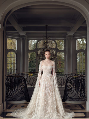 Long, dramatic caplet sleeve gown featuring beading and embroidered sequin lace, complemented by an A-line skirt with a train.