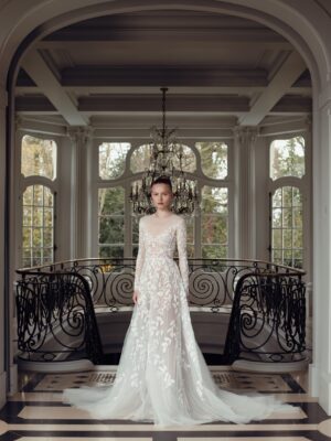 A beaded floral and leaf lace design with a scoop neckline, featuring sheer mesh accents and long sleeves, finished with an elegant, sweeping train.