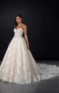 This blush ballgown features a sweetheart neckline adorned with intricate pearl and lace details. The bodice is complemented by a corset-style bisque waist, creating a flattering silhouette. The flowing skirt adds a touch of drama, making it a perfect choice for your elegant occasion.