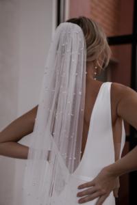 Our Pearl Veil features a single layer, 3-meter cathedral-length design adorned with delicate pearl detailing. It comes attached to a comb, making it effortless to secure in your hair.