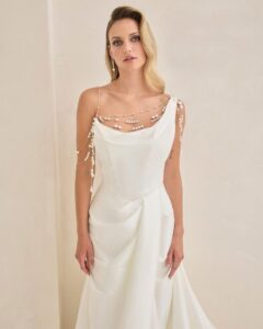 Bridal gown with asymmetrical neckline and pearl detailing.