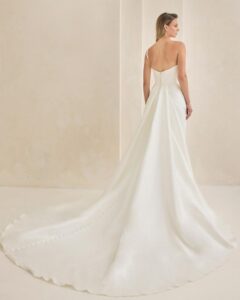 Bridal gown with asymmetrical neckline and pearl detailing.