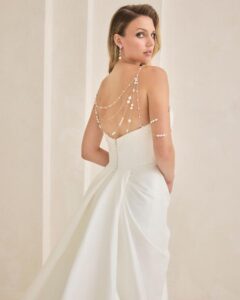 Bridal gown with asymmetrical neckline and pearl detailing.