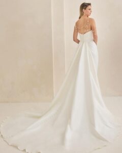 Bridal gown with asymmetrical neckline and pearl detailing.